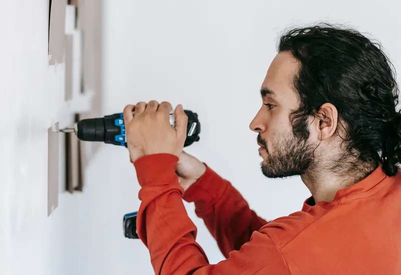 Handyman drilling into a wall to mount a fixture