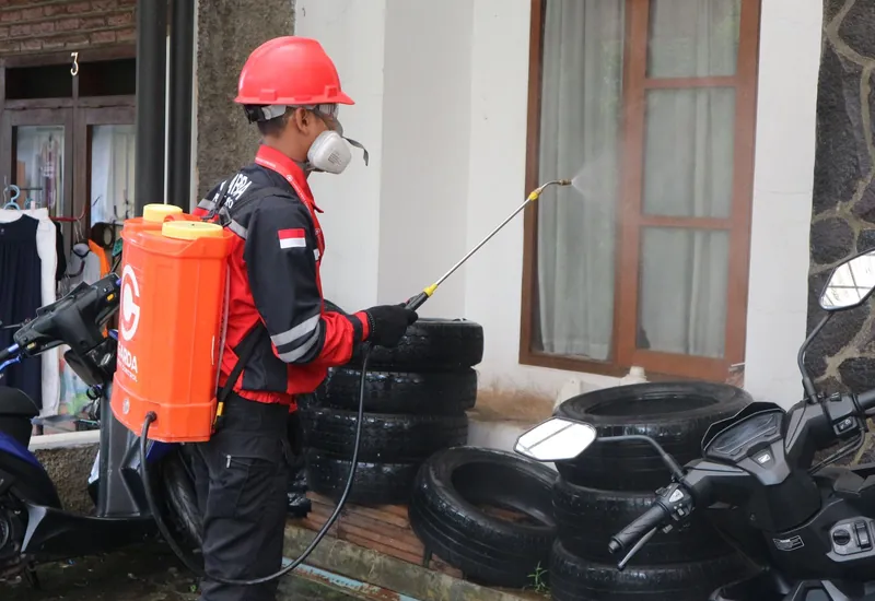 Pest control worker fogging a yard with a thermal fogger
