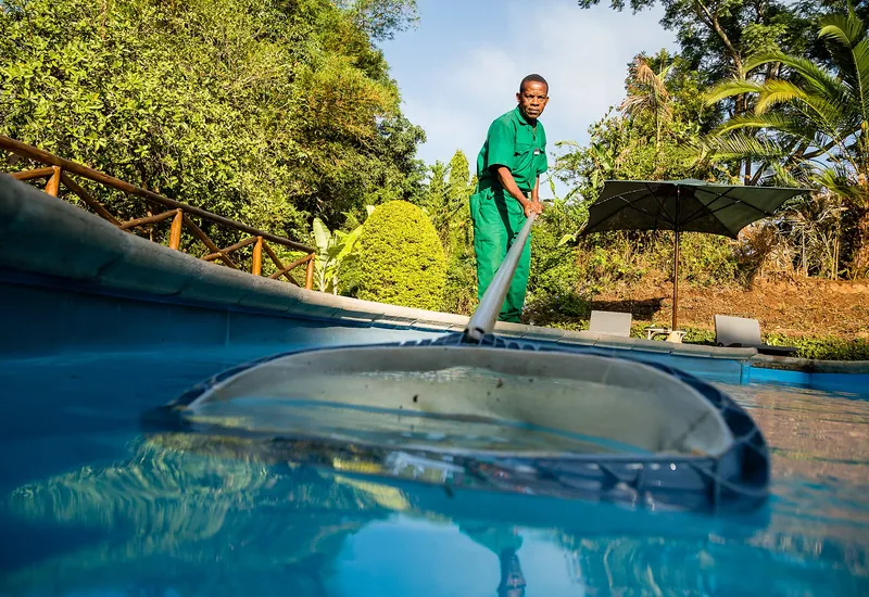 Pool technician cleaning a pool with a long pole