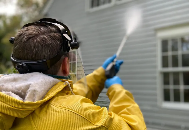 Worker pressure washing house siding
