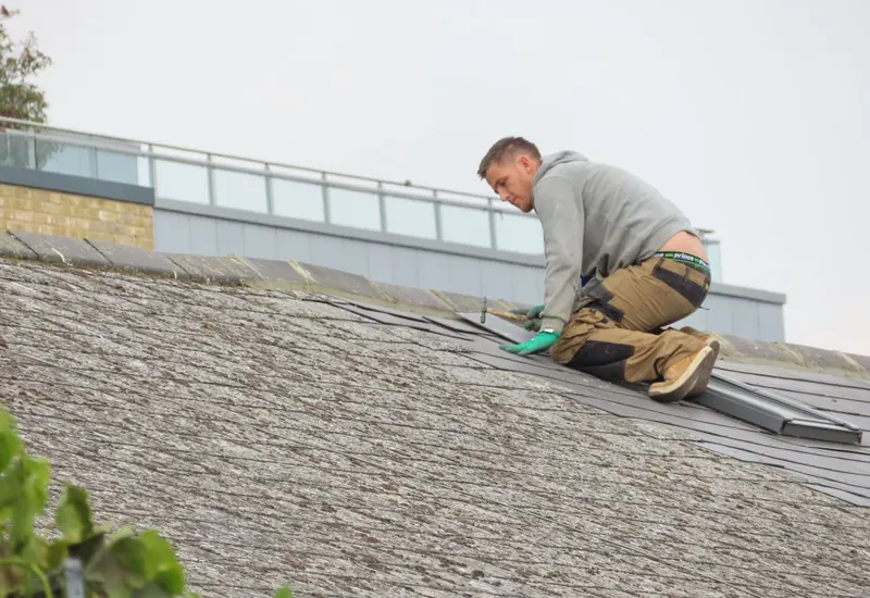 Roofer installing shingles on a rooftop